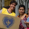 Una mamá de la Escuela Infantil San Francisco de Asís, recibe la Caja de Navidad, junto a su pequeño hijo.