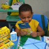 Rio de Janeiro, RJ — Com sorriso no rosto, criança exibe material pedagógico que recebeu da Instituição.
