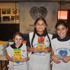 Student volunteers Sarai, Vernoica, and Julissa fill backpacks with school supplies for the Backpacks for a Bright Future campaign.