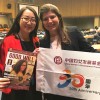 Representante de ONG e Executiva Sênior da China Women's Development Foundation, Guo Jingjing, recebe a publicação de Eliana Gonçalves, da LBV.
