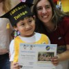 Thiago, egresado de la sala de  años de la Escuela Infantil Jesús, recibe su diploma, acompañado de su maestra.