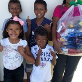 Araxá, MG — Na foto, a atendida Maria Kateane dos Santos Bispo posa, feliz, com os filhos e o presente que ganhou da Entidade.